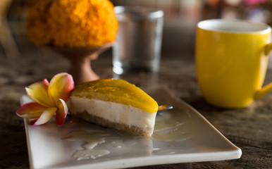 raw vegan cake with cashews and coconut and mango on top on wooden background