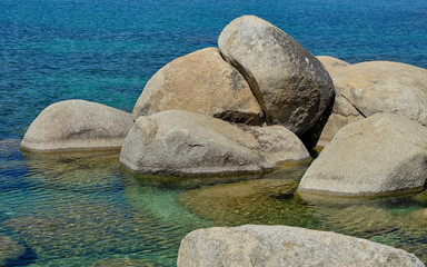 Fototapeta na wymiar Large granite boulders sit in he shallow and clear waters of Lake Tahoe