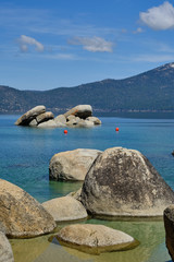 Fototapeta na wymiar Large granite boulders sit in he shallow and clear waters of Lake Tahoe