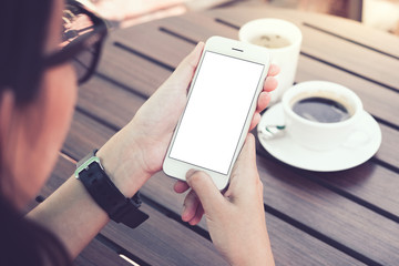 Woman holding smartphone with blank screen in cafe. clipping path.