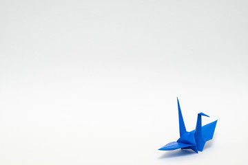 blue origami paper crane on white background - obrazy, fototapety, plakaty