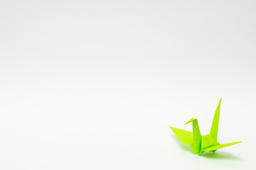 light green origami paper crane on white background