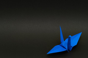 blue origami paper crane on black background