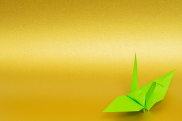 light green origami paper crane on golden background