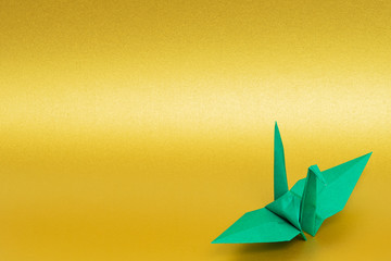 green origami paper crane on golden background