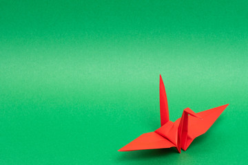 red origami paper crane on green background
