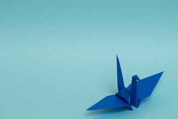 blue origami paper crane on sky blue background