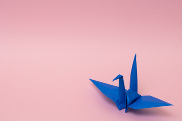 blue origami paper crane on pink background