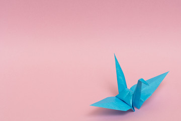light blue origami crane on pink background