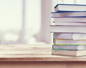 Collection of old books on wooden table on room background