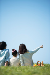 草原でピクニックをするファミリーの後ろ姿