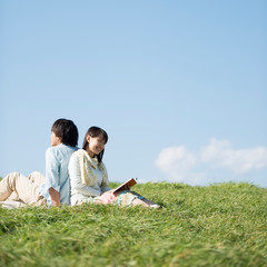 草原で音楽を聴く男性と読書をする女性