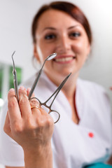 Beautiful, smiling dentist with tool in hand. Dentistry, dental treatment, health.