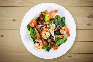 Spaghetti with shrimps, tomatoes and chopped parsley on wooden desk