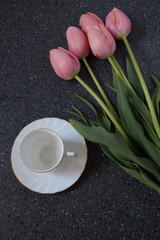 white tea cup with pink tulips on grey background