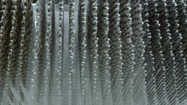 A huge number of drills stand in rows on the store shelf and shine in the light. Shot in motion