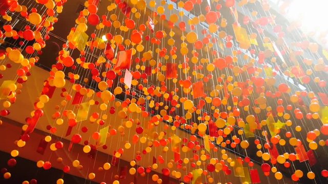 Hanging decotation from plastic balls and plates moving shining on sun