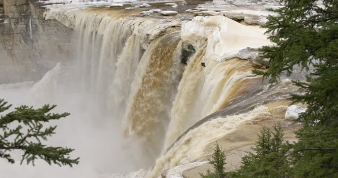 Beautiful shot of Alexandra Falls Northwest Territories during spring breakup. Lots of ice with trees in foreground