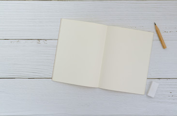 Flat lay of plain notebook with brown pencil and rubber on white background