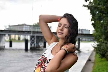 beautiful brunette girl with curly hair on the background of the bridge in summer