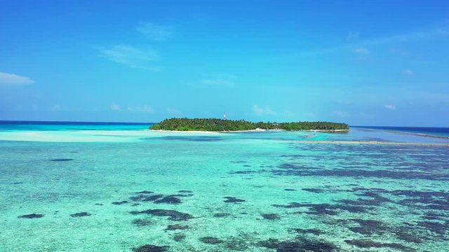 Flight over reefs and rocks in clear turquoise water in Indonesia. Flying towards an exotic island. Pedestal up, dolly in