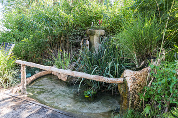 Decorative fountain in the bushes in the courtyard of the Beatitude Monastery located on the mountain on the coast of the Sea of Galilee - Kinneret