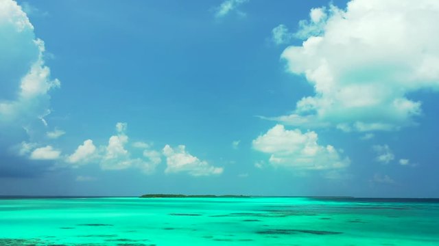 A blue sky with clouds above the turquoise  Philippine Sea.  one third of water. an island in the distance.