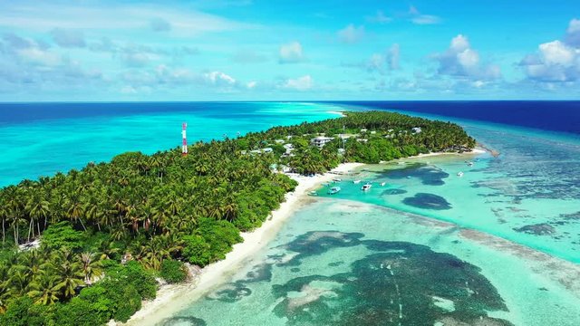 Aerial view of a tropical island with a forest and village in the background. The turquoise Sea of the Seychelles. Dolly out
