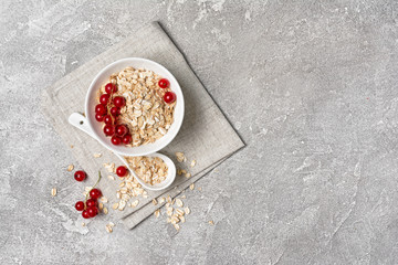 Oat flakes with red currant in white bowl for healthy breakfast