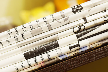 Pile of fresh morning newspapers on the table at office. Latest financial and business news in...
