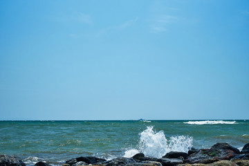 Image of the sea shore. In the background is a warship.