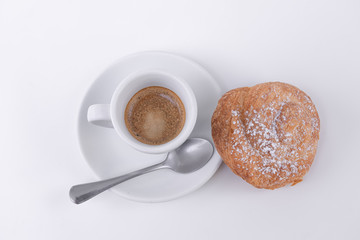 Tasty puff pastry roll with powdered sugar on top and a cup of hot coffee
