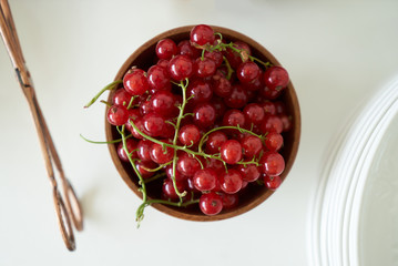 Red currant berry in a wooden bowl, close-up. Fresh currant fruit