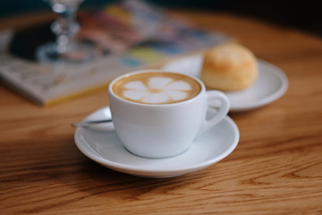 Cup of hot cappucino is on the wooden table.