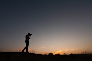 silhouette of man making photos at sunset with reflex camera