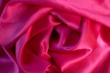 Silk fabric of a red shade. Luxury background, wavy texture.