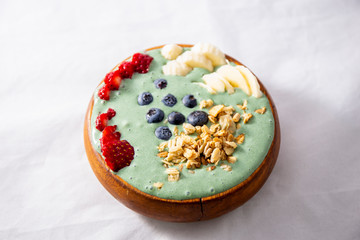 Spirulina yogurt with fruit in wooden bowl