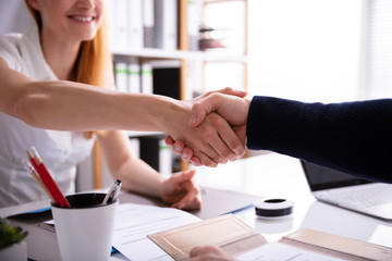 Businesswoman Shaking Hand With Her Colleague Over Desk