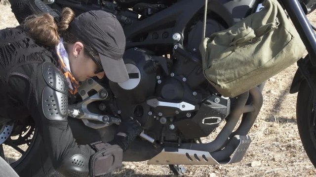 Young biker woman repair fixing  her motorcycle  on the old desert  road