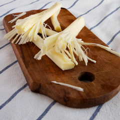 String cheese on a rustic wooden board on cloth, low angle view. Healthy snack. Closeup.
