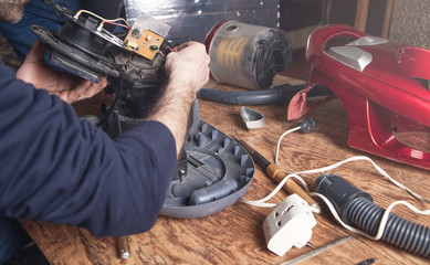 Man repairs of vacuum cleaner. Repairing