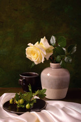 Still life with white rose and green gooseberries on the branch.