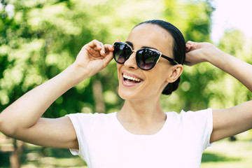 Stylish trendy young beautiful woman in sunglasses portrait. Woman in city park is posing