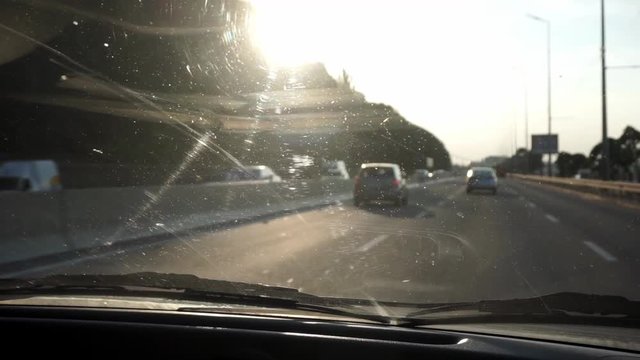 POV drive from car interior on city road toward sunset