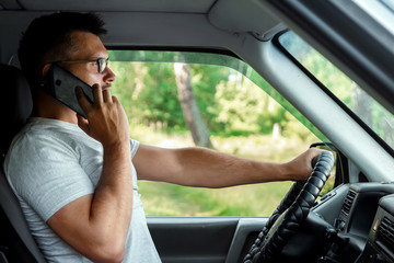 A man at the wheel holding a smartphone in his hand, violates traffic rules. The concept of an accident, a traffic violation, the phone at the wheel