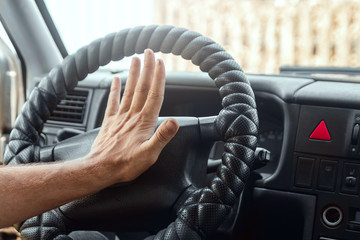 Male hand presses the signal on the steering wheel of the car. Close-up. Emergency, accident,...