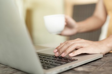 Fototapeta premium Working woman sitting. She is working with a notebook and is drinking coffee. The concept of women working with technology.
