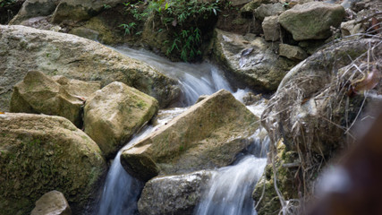 Naklejka na ściany i meble long exposure of creek water, with autumn leaf on rock.