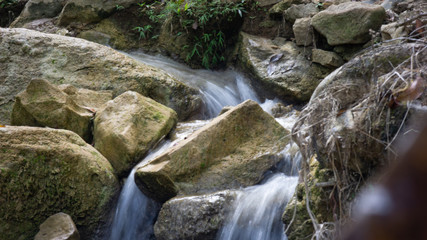 long exposure of creek water, with autumn leaf on rock.