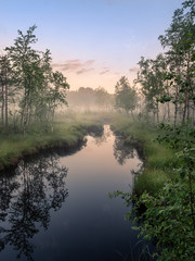 Idyllic river view with tranquil and foggy sunset at summer night in wetland, Finland